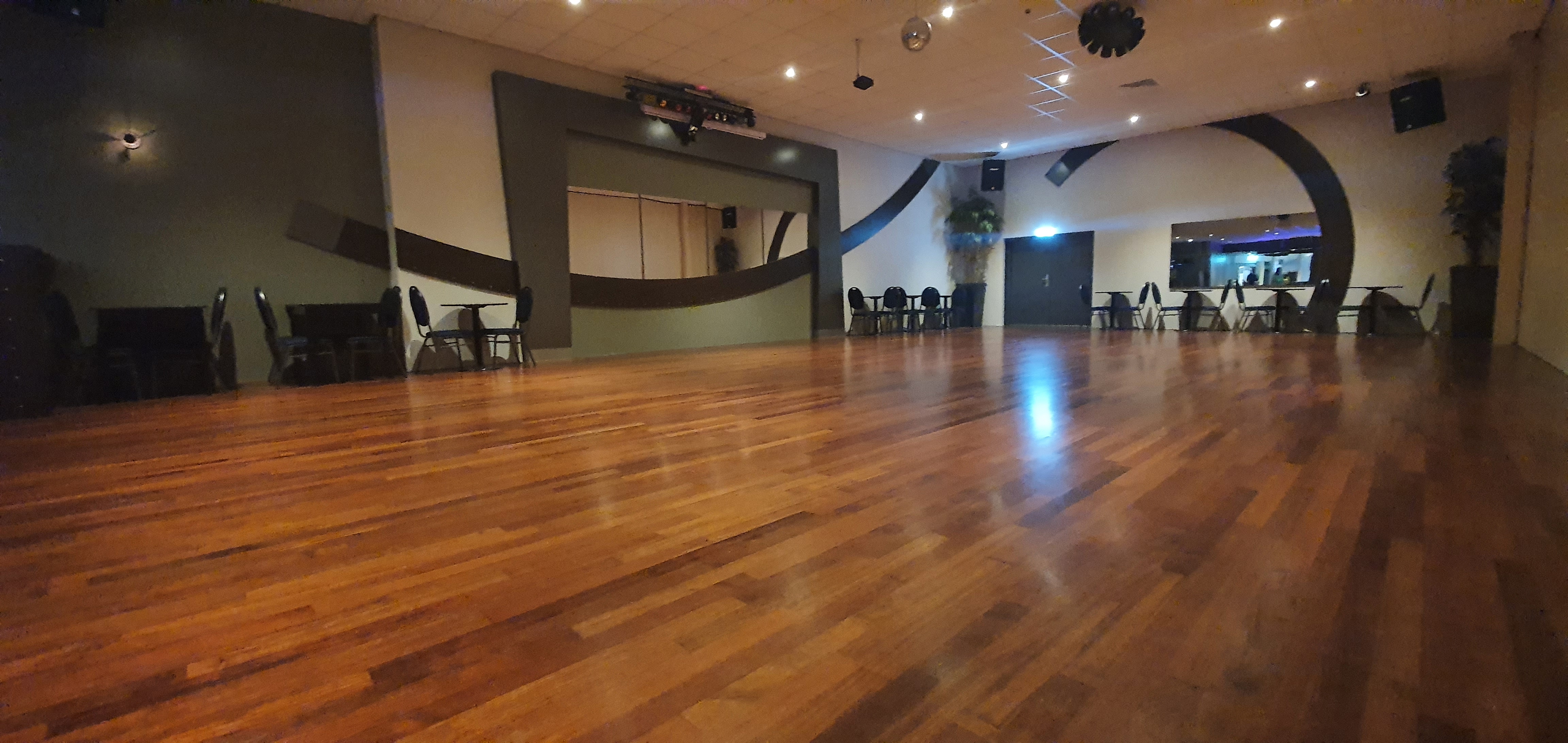 Grote zaal met houten dansvloer, bar en zitjes bij Van de Burgt